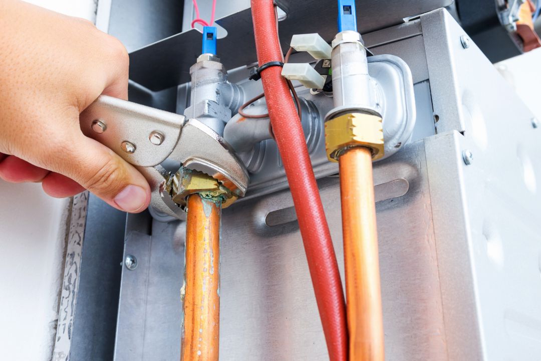 A plumber tightening the pipe connected to gas hot water system.